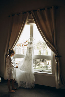 Woman admiring wedding dress near window; wedding photography Chicago by Monograin