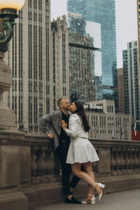 Couple kissing in city, surrounded by buildings. engagement photography, Monograin