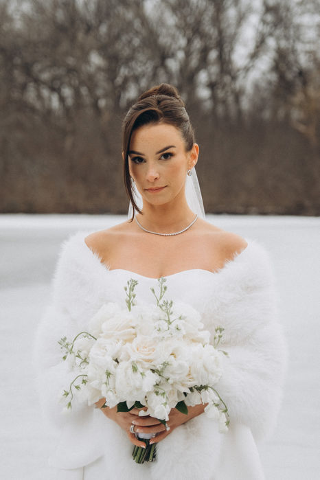 Bride in white fur wrap with bouquet, winter wedding scene.