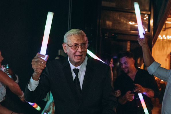 Smiling man with glasses holding light sticks at wedding photography Chicago.