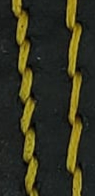Yellow thread on black leather, adding a bright highlight.