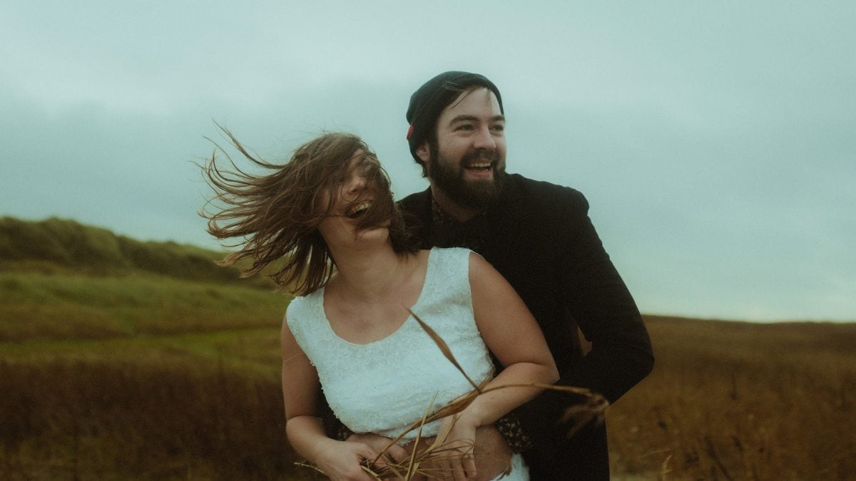 Elopement at the North Sea – a couple laughing together in the wild wind of Rømø, wrapped in joy and raw emotion. A candid moment that captures the untamed, intimate energy of a wedding far from the ordinary.
