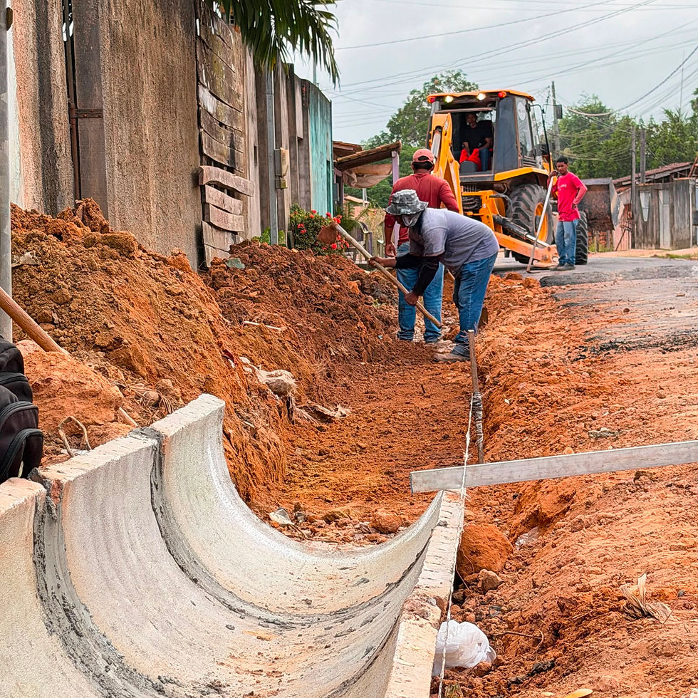 Trabalhadores da SETOURB abrem vala e posicionam manilha de concreto para instalação de canal de drenagem pluvial em rua de Tomé-Açu, com apoio de retroescavadeira.