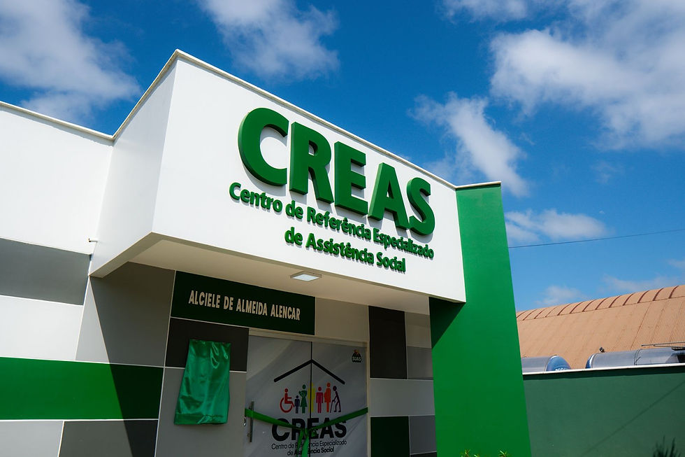 Fachada do CREAS branco e verde sob céu azul, com placa Centro de Referência Especializado de Assistência Social.