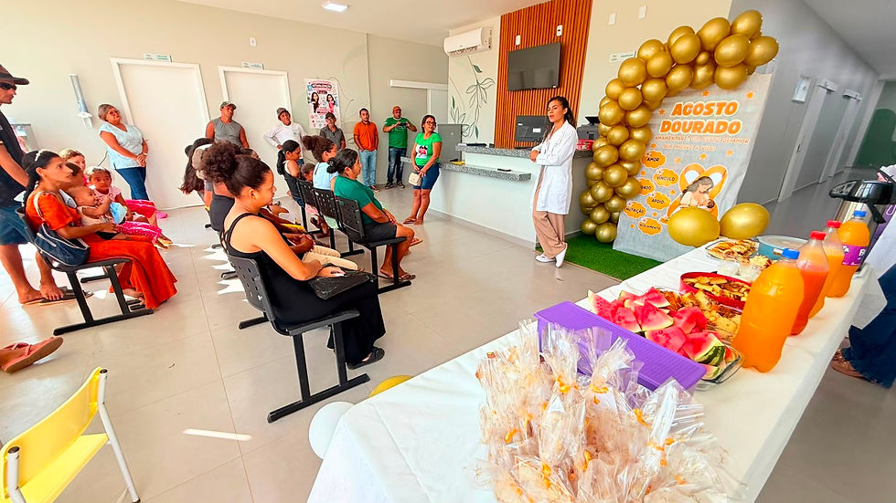 Profissional de saúde conduz palestra sobre aleitamento materno durante ação do Agosto Dourado em unidade de saúde de Tomé-Açu, com mesa decorada e lanche para os participantes.