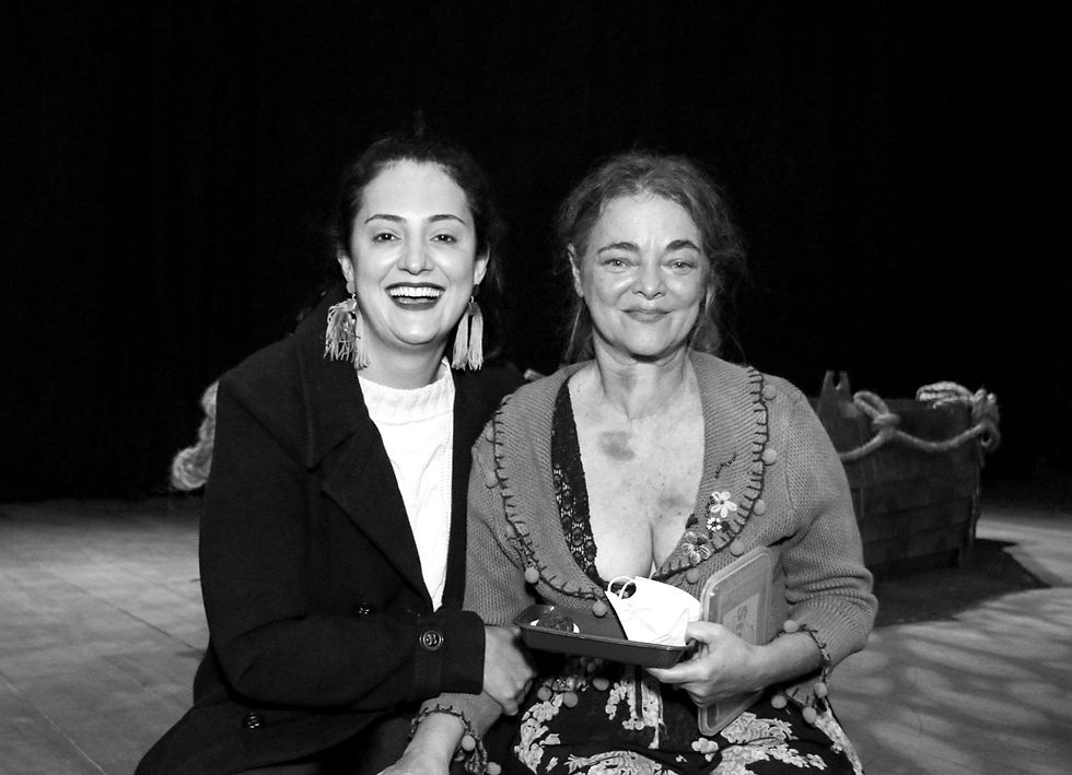 Aline e Inês posam para a câmera sentadas no palco depois da peça.