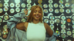 Sarah Sampp faz pose na frente de um mural de vinil e cds