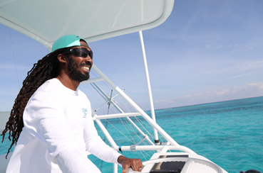 Turks and Caicos Local Captain Codney Capron guiding a private yacht charter on the 36' Benchmark Catamaran over clear waters near Grace Bay, Turks and Caicos.