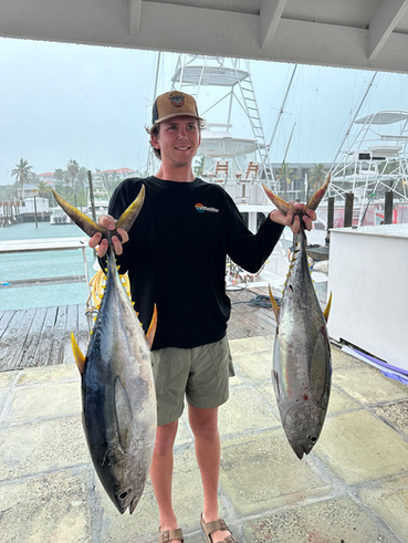 Guest holding two tuna after a deep‑sea fishing charter in Turks and Caicos.