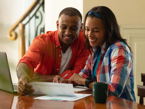 Young African American couple working on finances at a table with some paperwork and a laptop