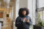 African American student walking through the school corridor on her cell phone