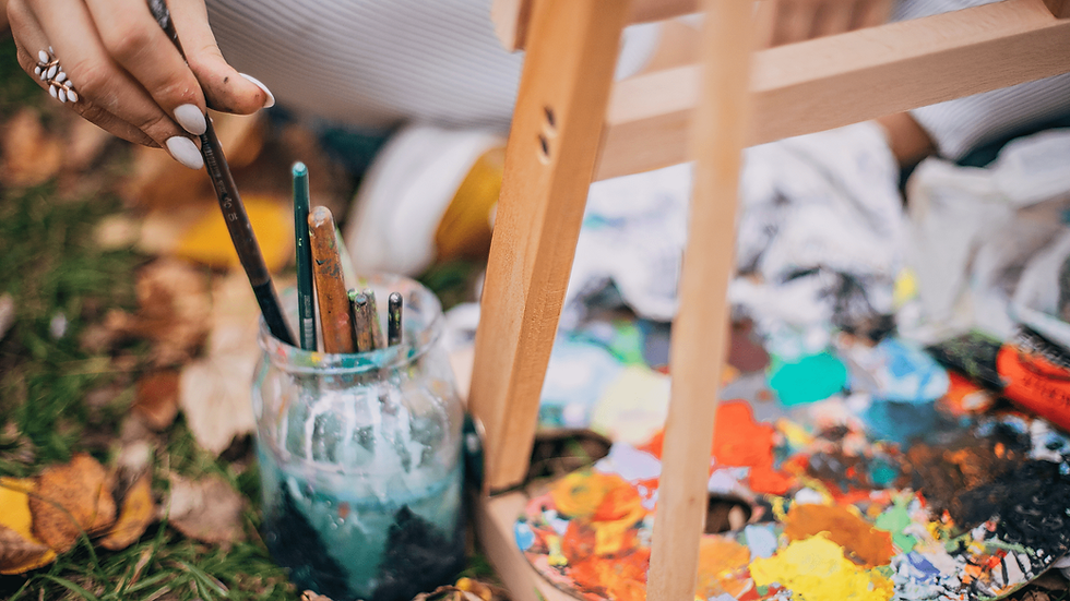 Woman artist painting with brush and palette, creative process, close-up view.