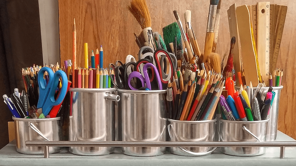Assorted art supplies in metal containers, including pencils, scissors, and brushes.