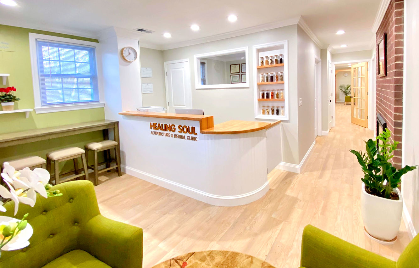 Healing Soul Clinic's front desk area with a cozy seating area, tea station, and hallway leading to treatment rooms.