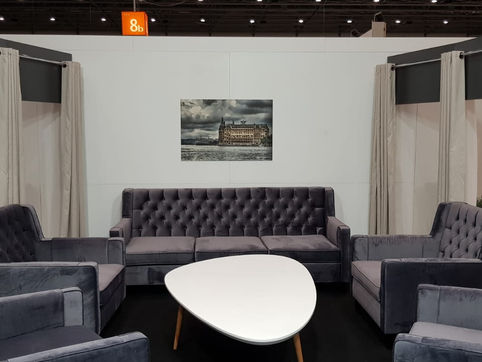 Modern oturma alanı, gri kadife koltuklar, şık beyaz sehpa ve tablo.