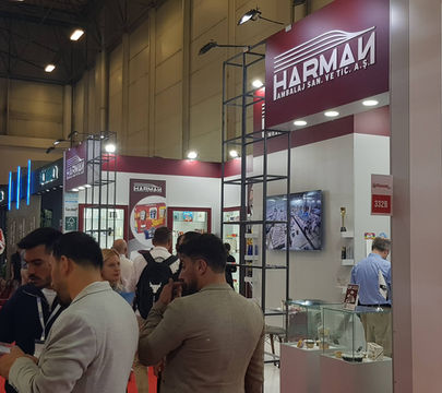 HARMAN fuar standı, kalabalık insanlarla dolu, fuar alanında sergileniyor. HARMAN standı.