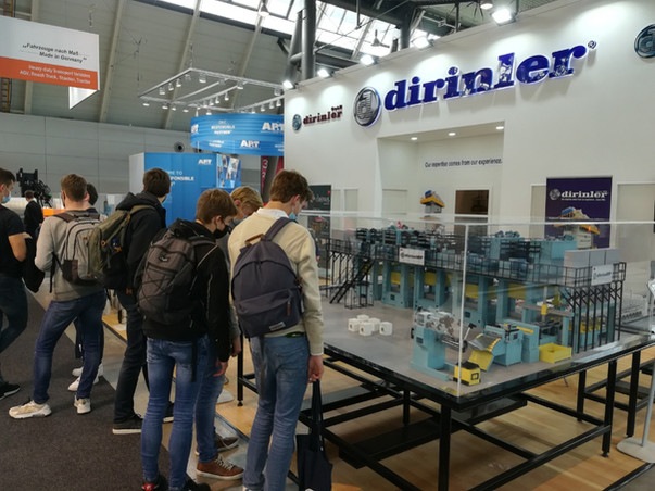 Dirinler fuar standında makine modelini inceleyen ziyaretçiler.