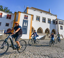 Tourists in a magical e-bike tour in Sintra in front of the National Palace of Sintra