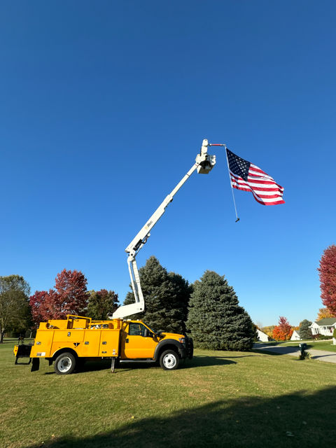 Bucket truck in yard with an American flag