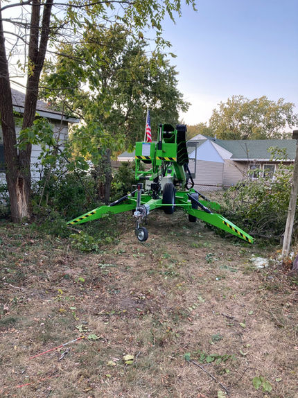 tow behind spider lift trimming trees overhanging a house