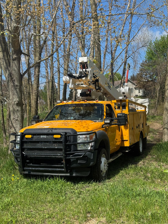 Bucket truck is parked in yard near trees