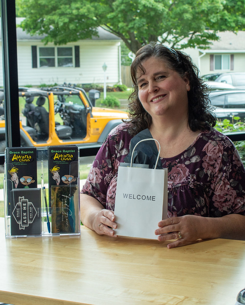 A woman smiling at a welcome desk while holding a guest gift bag