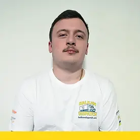 Professional portrait of George S wearing a white Balkan Dispatch branded shirt