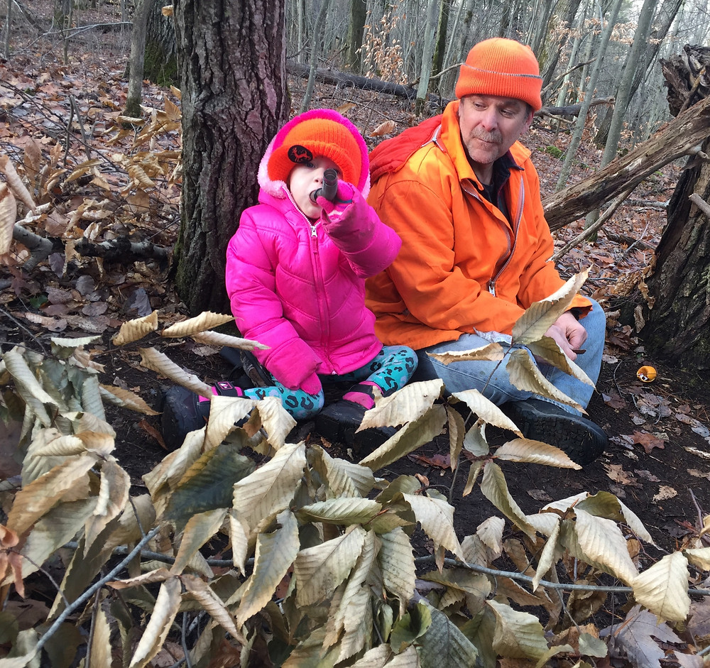 Grandpa teaching granddaughter how to use a deer call.