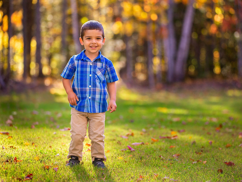 A boy posing for a portrait outside in the fall
