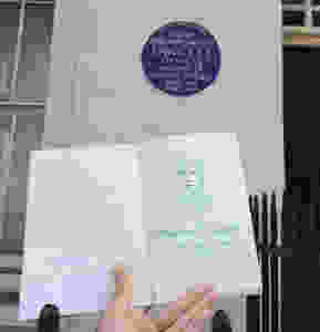 Nina holding up a sketch of Dame Millicent Garrett Fawett next to her blue plaque in London.