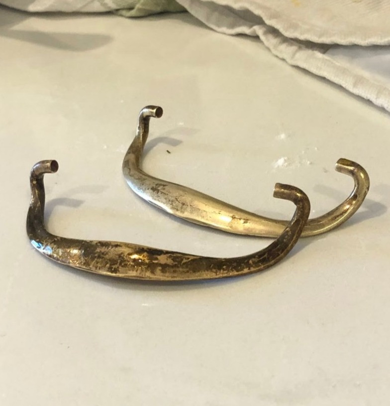 Polished brass hardware for a traditional refinished nightstand.