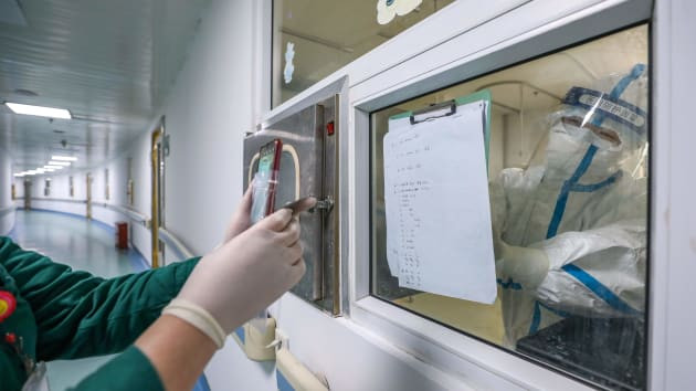 Nurse Cao Shan, right, working in the isolation ward, shows the conditions of a patient to a co-worker in Jinyintan Hospital. She and her husband, a doctor also working at the hospital, have slept in the vehicle for 23 nights to avoid bringing viral hazards around, save commuting time, and give their assigned nearby hotel room to colleagues.