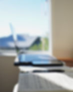 Laptop set up in sunny room with notebook