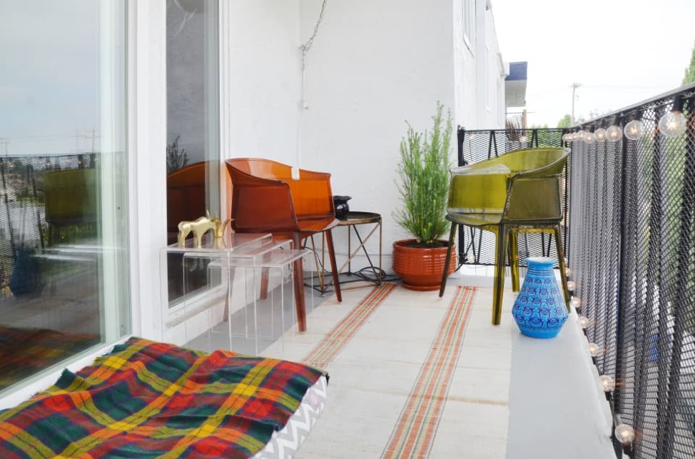Want to be the talk of the town for your trending ideas to decorate a small balcony? Then, this vibrant, colorful, and eclectic mix of outdoor styles is what you should aim for. Created with these magnificent lucite chairs, this warm color pallet creates nostalgia of the ‘70s. However, this chic rug, planters, and outstanding chiminea provide a precise Mediterranean vibe.