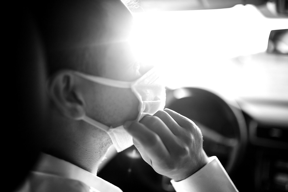 Driver inside car adjusting the mask covering his nose and mouth