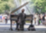 A photo of a pianist in the middle of strolling tourists and New Yorkers in Central Park, accompanied by the fountain in the back. Music is everywhere in the walkable city of New York. Walkable Cities is an eco-friendly activity as a tourist which makes New York ideal for your Eco Travel Destination.