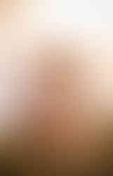 Mom and dad share a kiss with son in-between them looking at camera