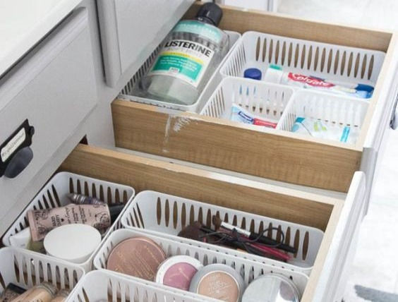 Plastic baskets with makeup and small items inside bathroom drawers