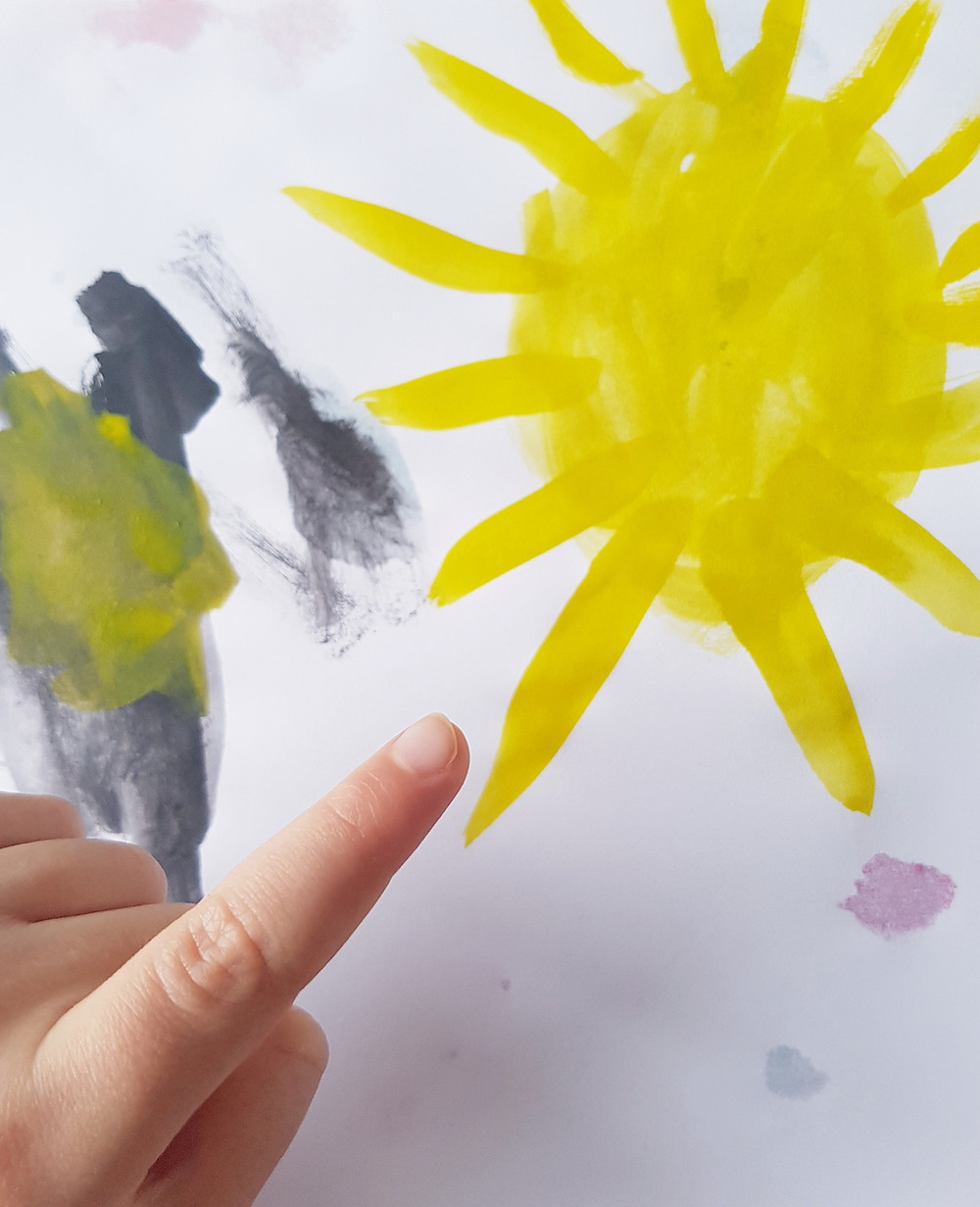 Child pointing at painting of sun