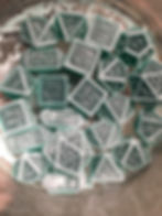 Pile of dice at the bottom of a glass container. Very light green, almost white dust is highly visible on all edges and surrounding the pile.