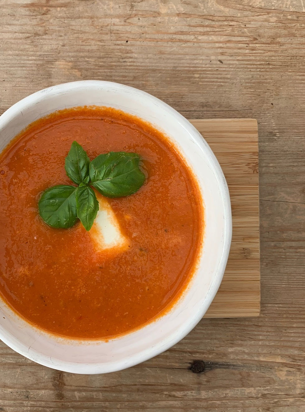 Tomatsoppa i skål med fetaost och basilika
