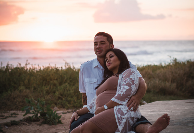 Couple cuddling gazing out to the water during sunset