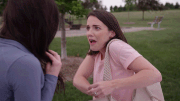 An excited brunette showers another woman with confetti pulled from her purse