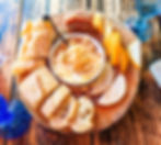 baked brie served with French baguette bread, pears, and date jam