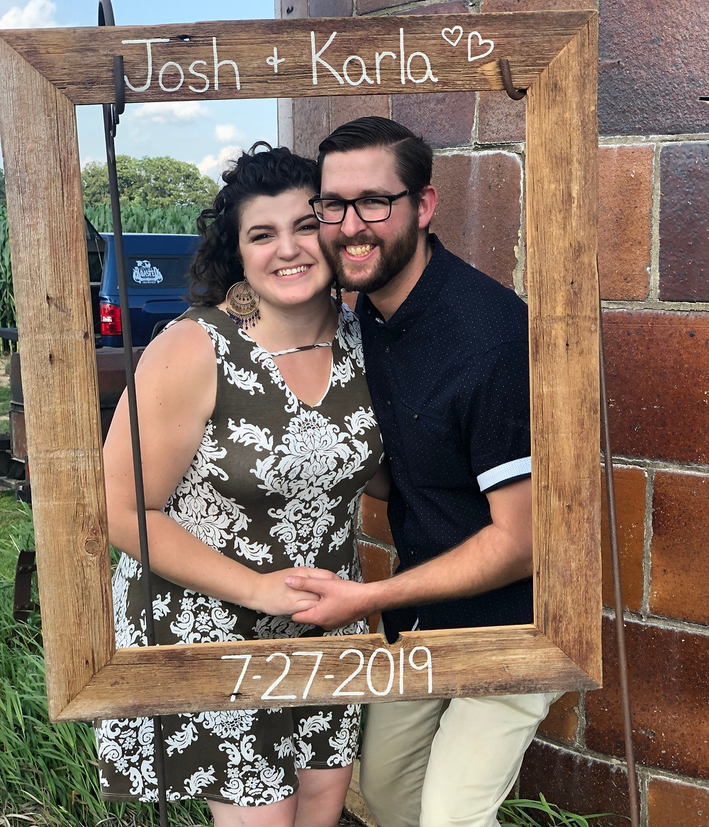 A woman and man pose in a photobooth at a outdoor Wisconsin wedding ceremony