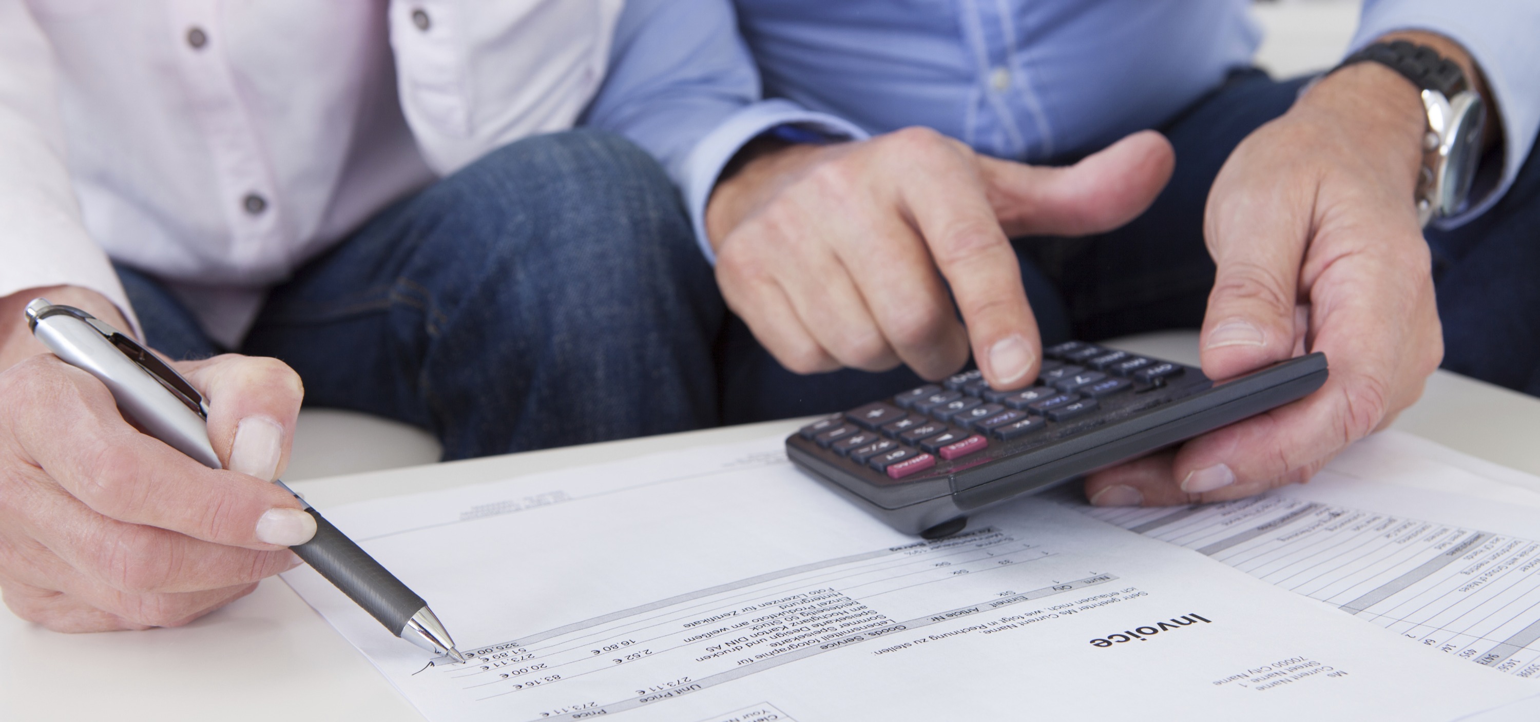 Una mujer y un hombre, ambos emprendedores autónomos, revisan detalladamente datos financieros y realizan cálculos con una calculadora. Esta imagen representa la planificación y gestión fiscal para la mujer autónoma y su colaborador, asegurando un control efectivo de sus finanzas. ¡Emprende con seguridad y controla tus números para el éxito de tu negocio!