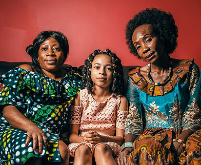 Three generations of Black women sitting on a couch.