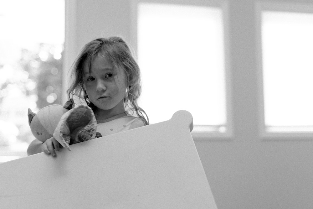 Young girl pouting with puppets in front of sunlit windows