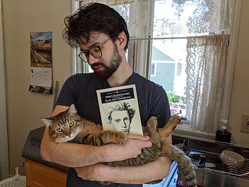 Ilango Villoth, with his cat Whiskey, holding his copy of "Fear and Trembling"
