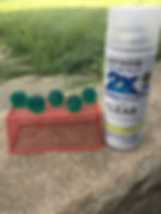 Dice outdoors on top of a mesh metal box with can of clear gloss spray paint next to it.